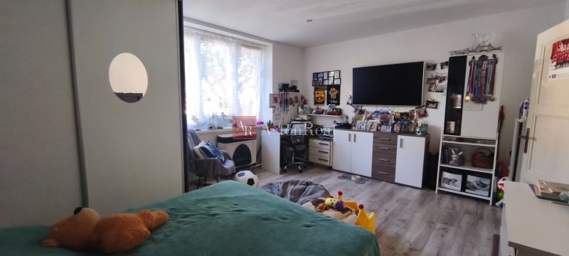 A room in a one-bedroom apartment with a bed, a desk, and a TV on the wall.