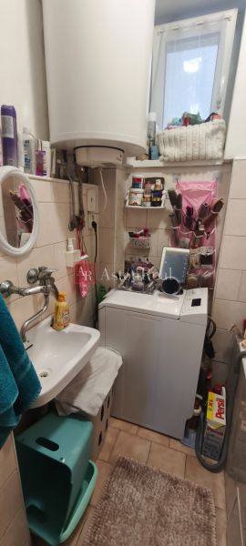 Compact bathroom with a washing machine, sink, and storage spaces in a studio apartment.