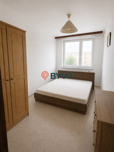 A bedroom in a 3-room apartment with wooden furniture and a chandelier in neutral colors.