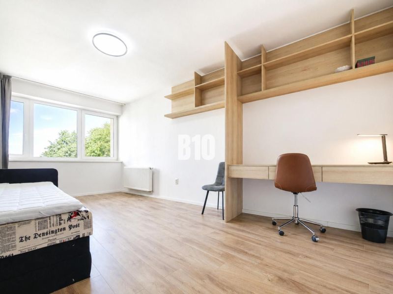 Recreational apartment with a bed, desk, chair, and floor with wooden decor.