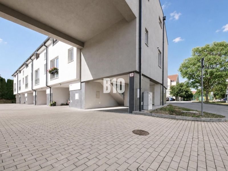 Exterior of the Holiday Apartment in Nitra with a paved courtyard and green vegetation.
