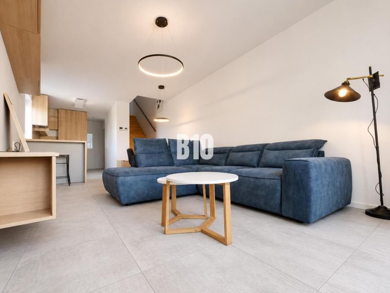 Recreational apartment with a blue sofa, a rectangular table, and plenty of light in the interior.