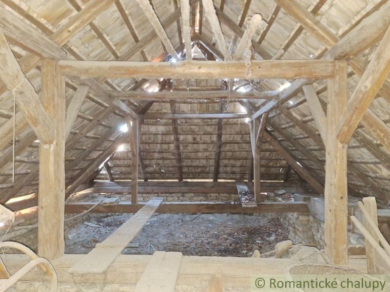 Attic with a wooden beam ceiling and light penetrating through skylights.