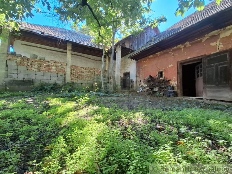 An older house with a garden and a crumbling facade in Nová Vieska, suitable for residential land.