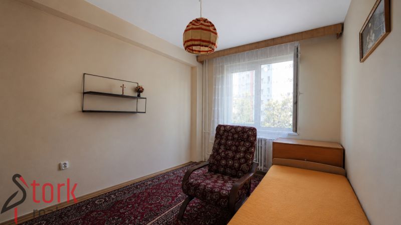 A room in a 3-room apartment with a sofa, a shelf, and a carpet, a view of the street.