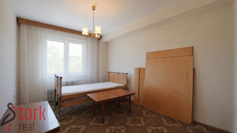 A bedroom in a 3-room apartment with a bed and a table, with a traditional carpet.