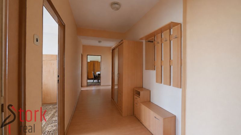 A hallway in a 3-room apartment with a wooden decor floor and a built-in wardrobe.