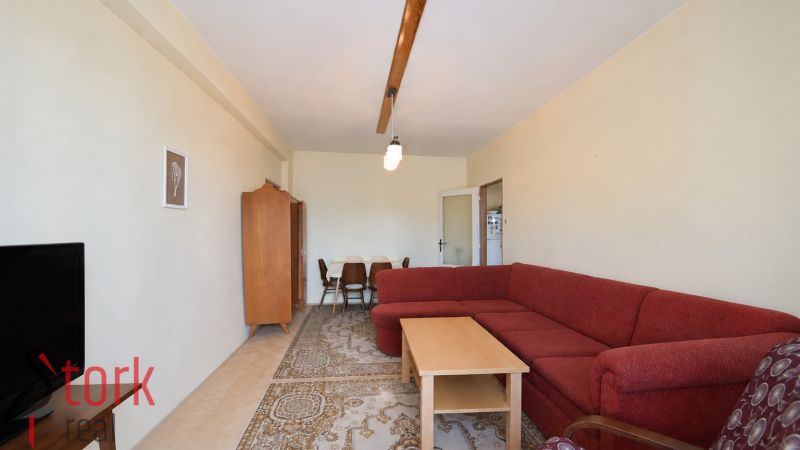 Living room in a 3-room apartment with a red sofa and a wooden decor floor.