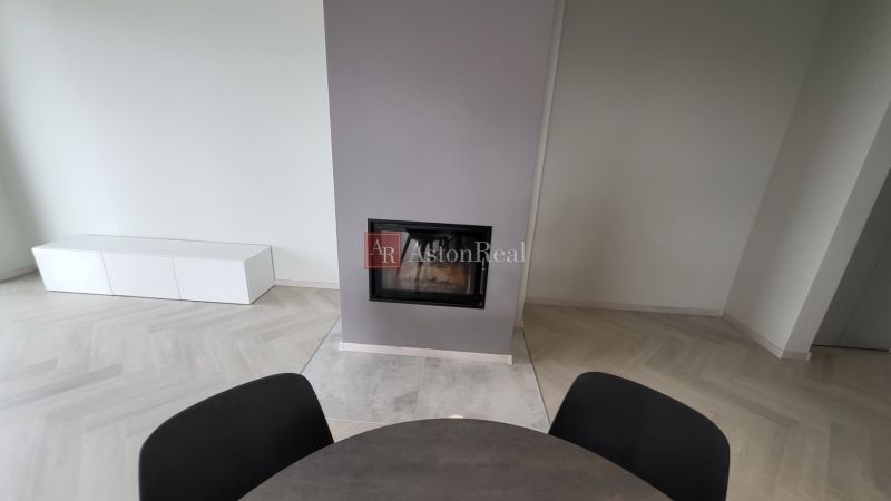 Fireplace, round table, and light floor with wooden decor in a 3-room apartment.