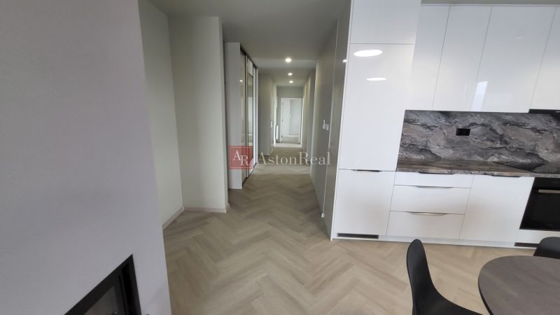 The hallway of a 3-room apartment with a wooden decor floor and a kitchen unit.