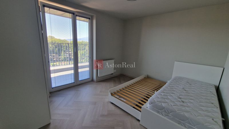 A bedroom in a 3-room apartment with a bed and a wooden decor floor.