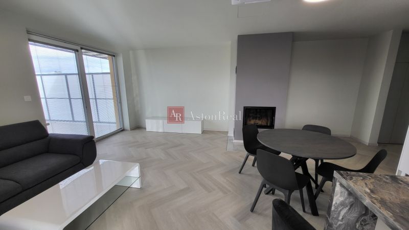 Living room in a three-room apartment with a wooden decor floor and a fireplace.