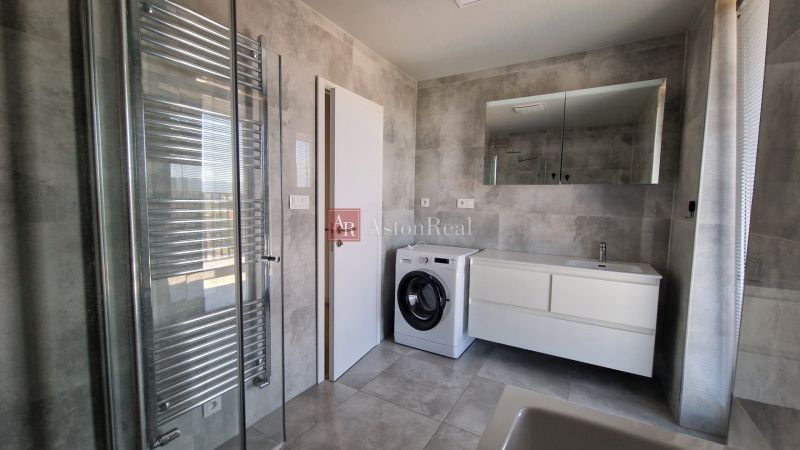 Modern bathroom with a washing machine in a 3-room apartment, gray tiles and a shower corner.