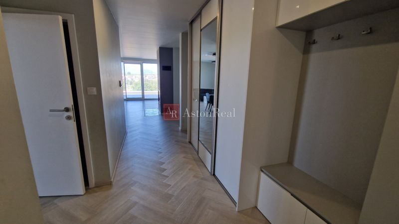 A hallway in a 3-room apartment with a wooden decor floor and mirrored wardrobes.