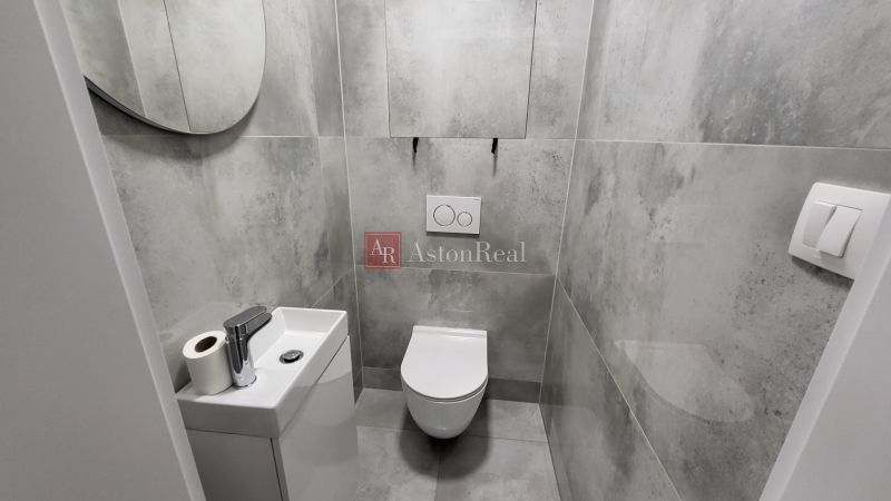 Gray bathroom with a toilet and a small sink in a 3-room apartment.