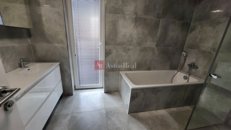 Bathroom with a bathtub and a sink, tiles in gray tones, part of a 3-room apartment.