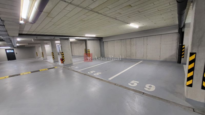 Parking spaces in an underground garage with numbers marked on the concrete floor.