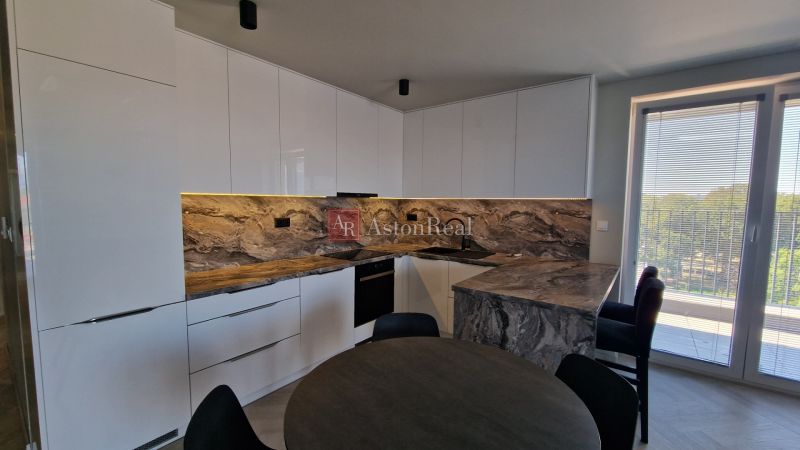 A kitchen with marble decor in a 3-room apartment and a window to the balcony.