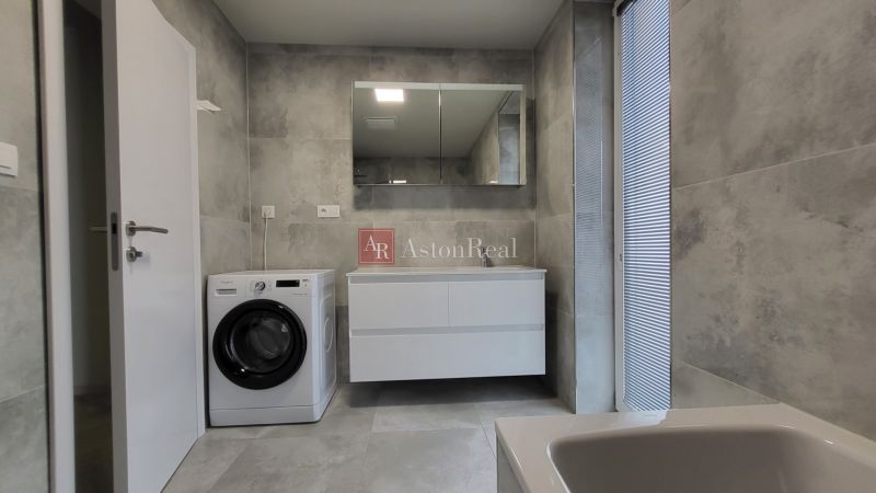 Bathroom in a 3-room apartment with a washing machine, sink, and mirror, gray tiles.