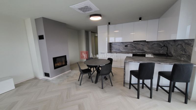 Living room of a three-room apartment with a wooden decor floor and a kitchenette.