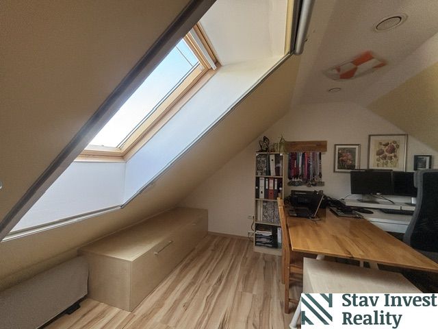 An attic office with a skylight and a wooden decor floor in a 4-room apartment.