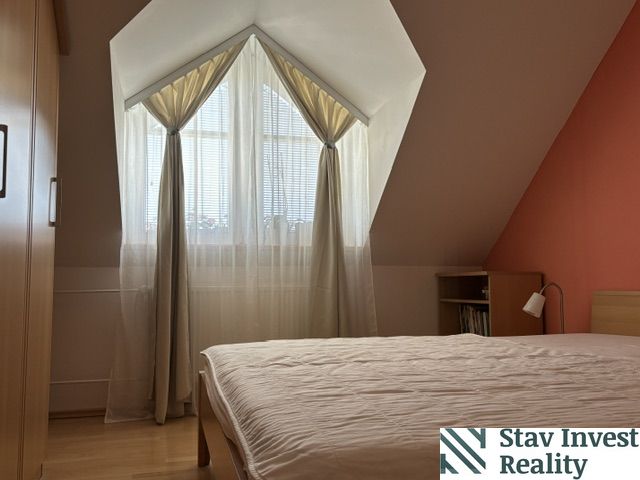 A bedroom in a 4-room apartment with a wooden decor floor and a slanted ceiling.