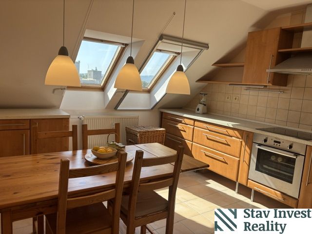 A kitchen in a 4-room apartment with a wooden decor floor and slanted roof windows.