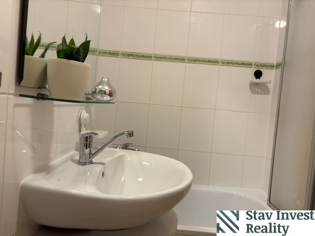 A bathroom with a mirror and a sink in a 4-room apartment with white tiles.