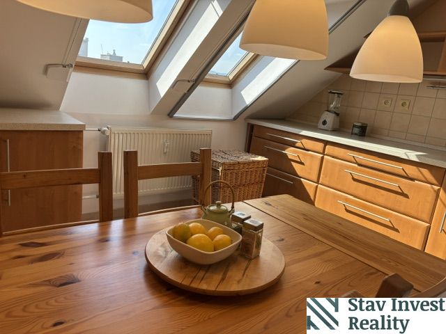 A kitchen in a 4-room apartment with a wooden decor floor and skylights.