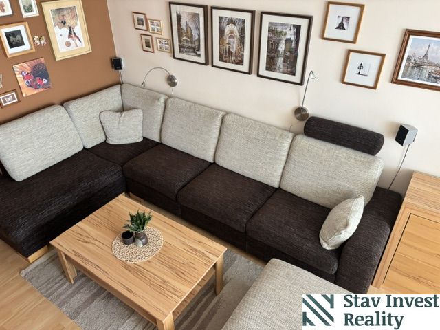 A living room in a 4-room apartment with a sofa and a wall with artworks.