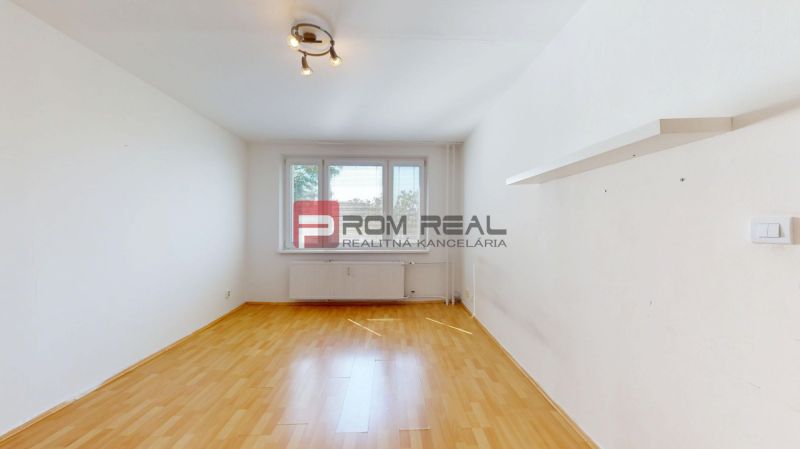 A room with a wooden decor floor, light walls, and a built-in shelf in a 3-room apartment.