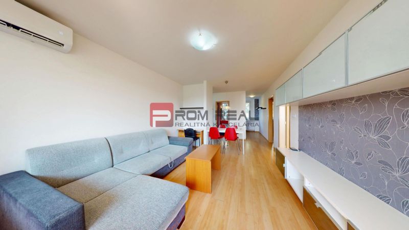 Living room in a 3-room apartment with a sofa, dining table, and wooden-patterned flooring.