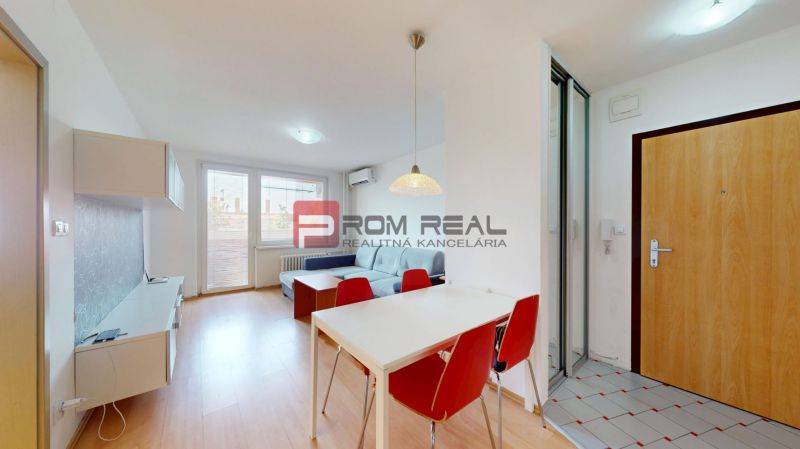 Living room of a three-room apartment with a wooden decor floor, dining table, and sofa.