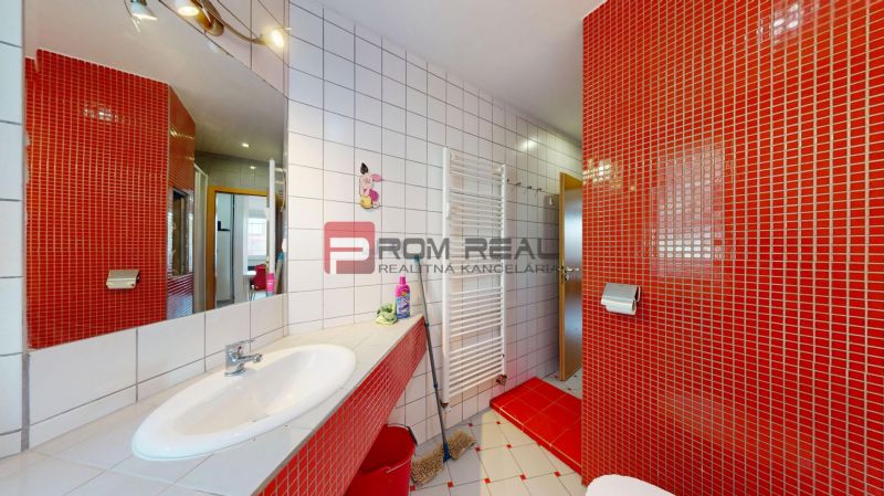 A bathroom with a mirror and striking red mosaic in a 3-room apartment.