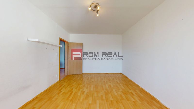 A room in a 3-room apartment with a wooden decor floor and spot lighting.