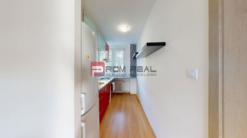 A narrow kitchen in a 3-room apartment with a kitchen unit and a wooden decor floor.