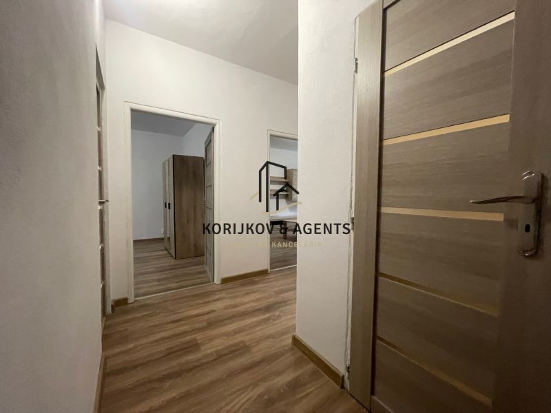 Interior of a 2-room apartment with a wooden decor floor and light walls.