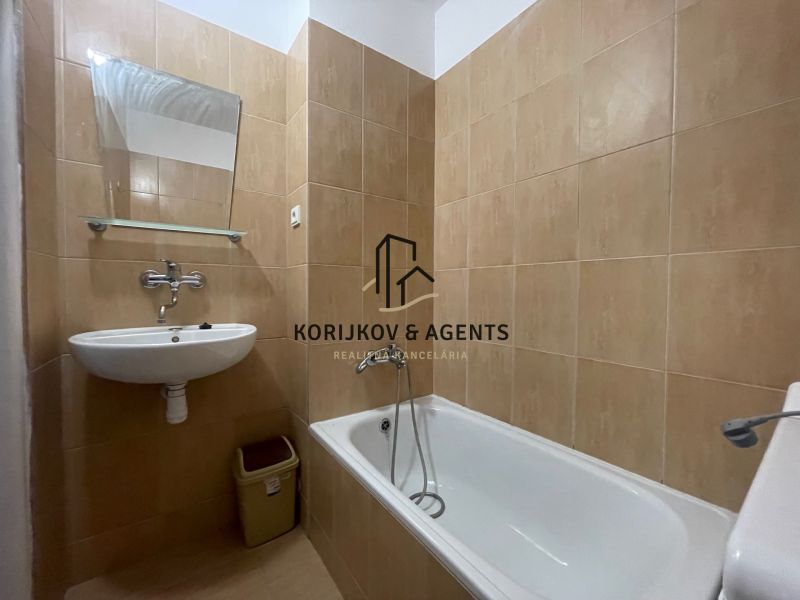 A bathroom with a white bathtub and sink in a two-room apartment.