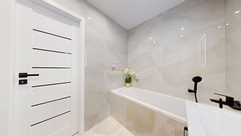 Bathroom in a 3-room apartment with a bathtub, white doors, and black hardware.