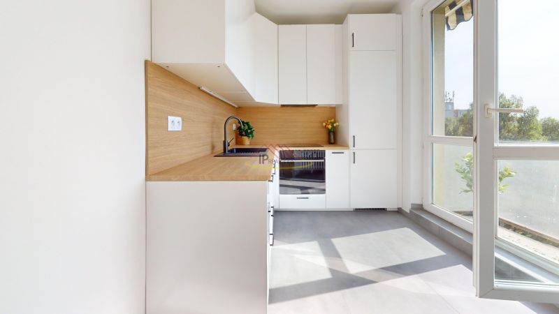 A kitchen in a 3-room apartment with white cabinets and a wood-patterned floor.