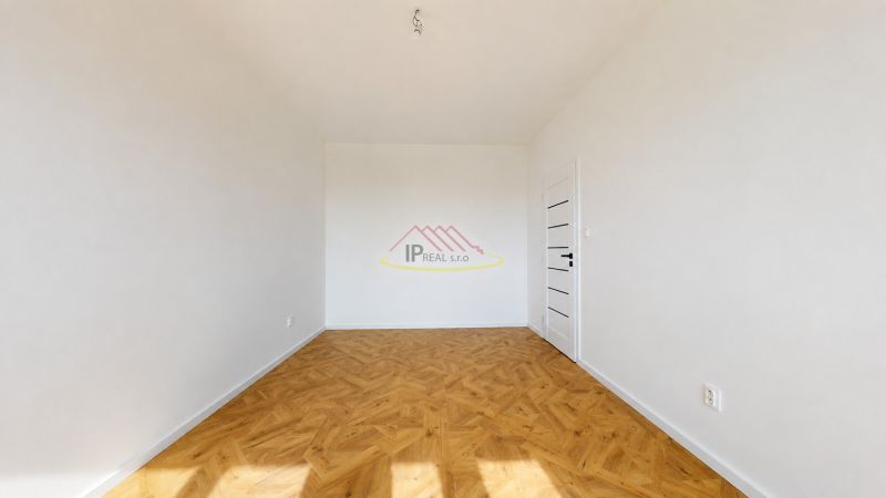 A room in a 3-room apartment with a wooden decor floor, white walls, and doors.