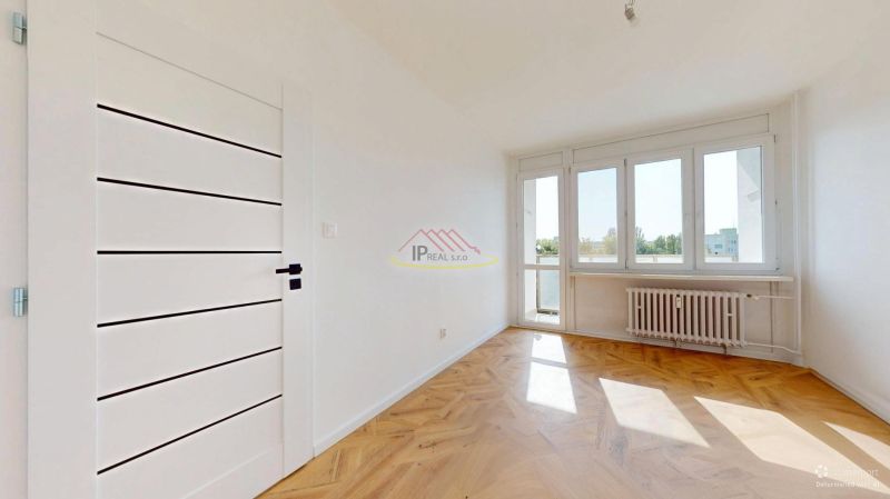 A bright room in a 3-room apartment with access to a balcony and a floor with a wooden decor.