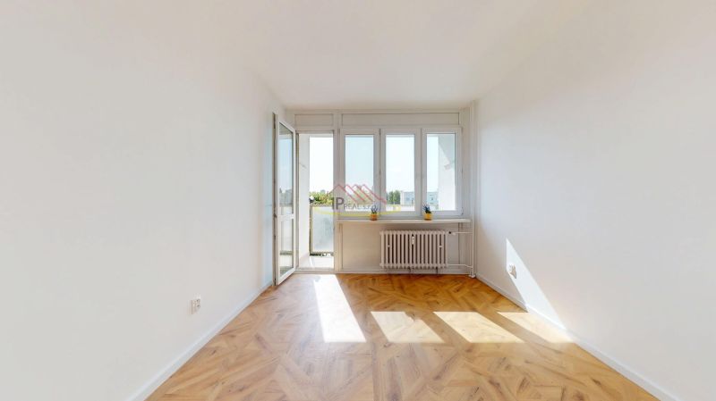 A room with a bright interior, a balcony, and a wooden decor floor in a 3-room apartment.