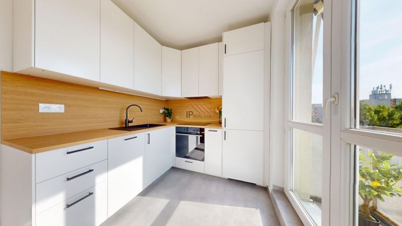 A kitchen in a 3-room apartment with white cabinets and a wood-patterned floor.