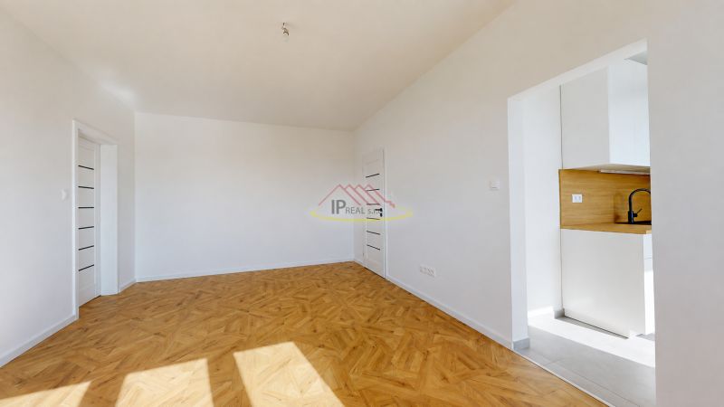 A bright room in a 3-room apartment with a wood-patterned floor and a kitchen nook.