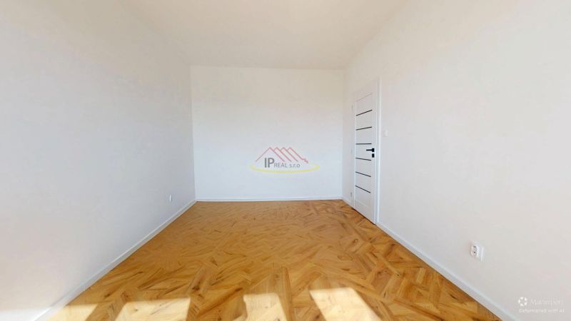An empty room with white walls and a wooden decor floor in a 3-room apartment.