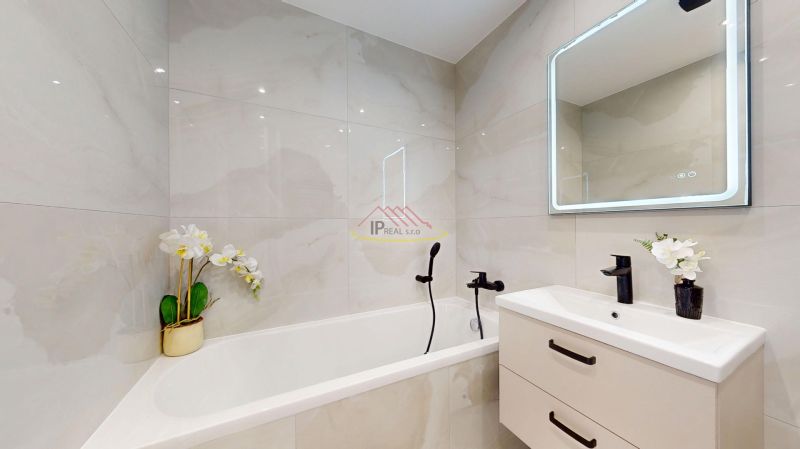 Bathroom in a 3-room apartment with a bathtub, mirror, and decorative flowers.