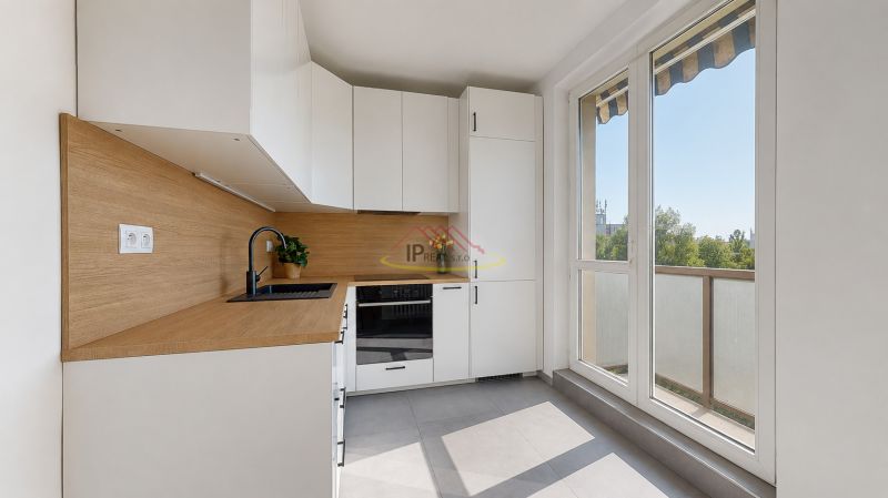 A kitchen in a 3-room apartment with white cabinets and a wood-patterned floor.