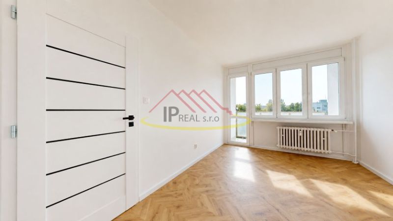 Bright room with wood-patterned flooring and large windows in a 3-room apartment.