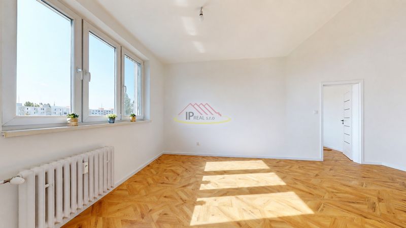 A bright room with large windows and a wooden decor floor in a 3-room apartment.